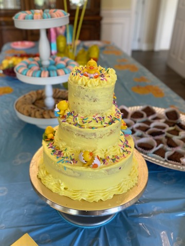 Three-tier yellow baby shower cake decorated with ducks