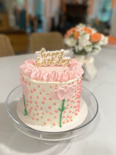 White birthday cake with pink piped flowers